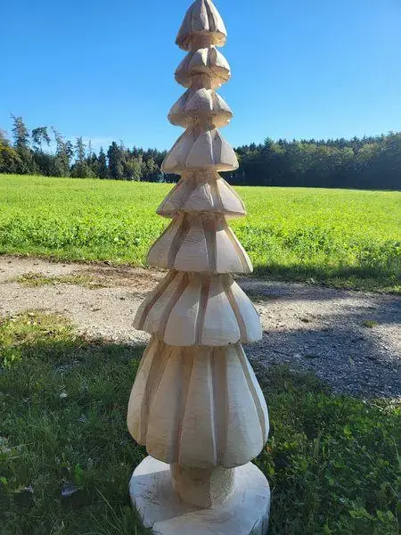 Weihnachtsbaum aus geschnitztem Holz auf einer Wiese