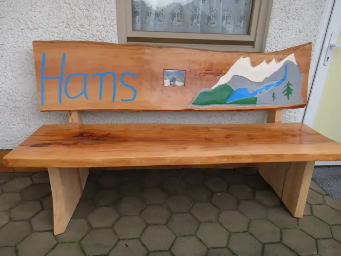 Holzbank mit eingeschnitztem Namen und gemaltem Bergmotiv