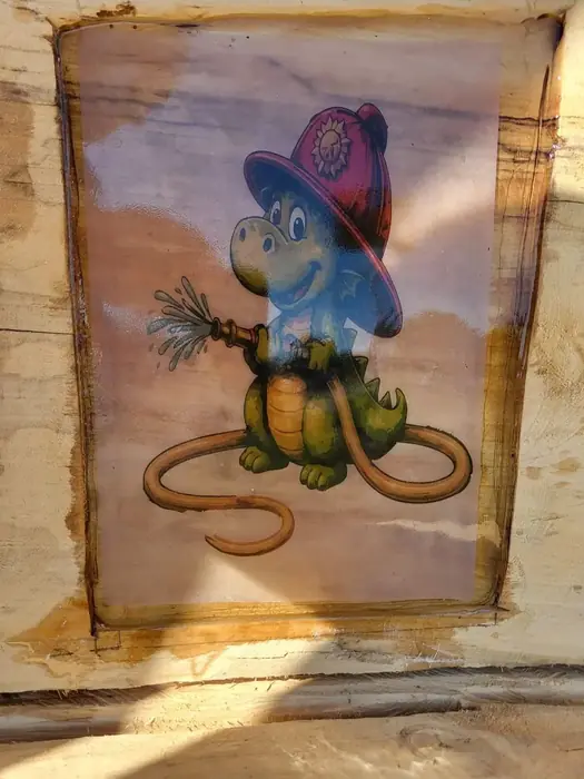Auf Holz gemaltes Motiv mit einem Frosch als Feuerwehrmann