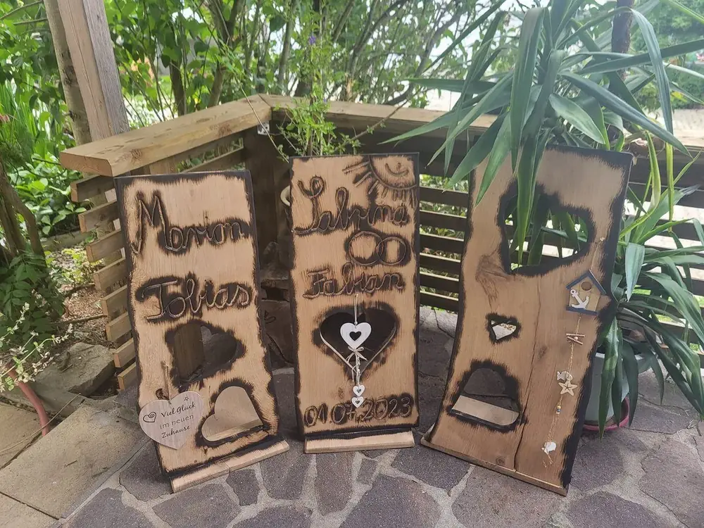 Mehrere geschnitzte Holztafeln mit Namen und Herzmotiven