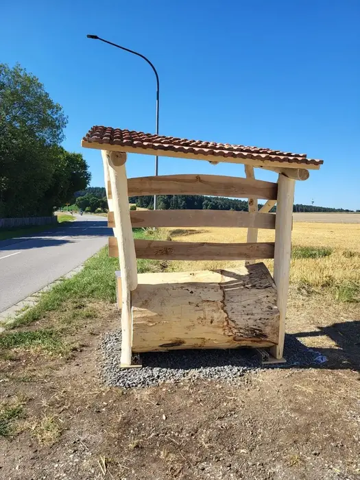 Selbst gebautes Wartehäuschen aus Holz mit Ziegeldach an einer Landstraße